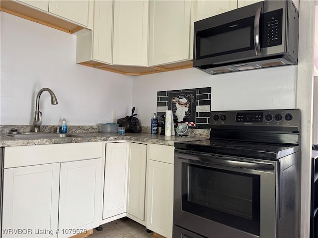 kitchen with backsplash, white cabinetry, stainless steel appliances, and a sink