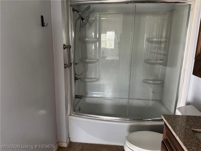 bathroom with combined bath / shower with glass door, toilet, and vanity