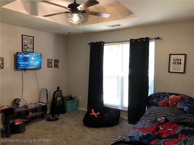 bedroom featuring a raised ceiling, ceiling fan, and carpet floors