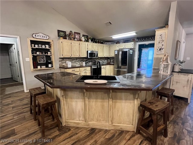 kitchen featuring a breakfast bar, lofted ceiling, backsplash, sink, and appliances with stainless steel finishes