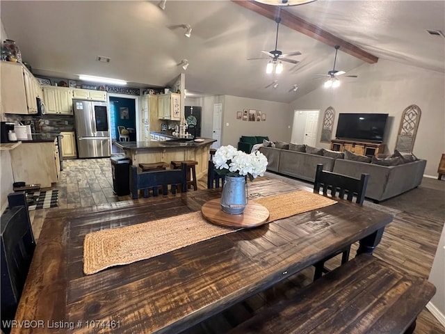 dining space with vaulted ceiling with beams, ceiling fan, and dark wood-type flooring