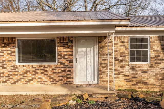 property entrance featuring brick siding and metal roof