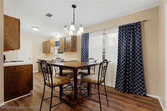 dining area featuring sink, an inviting chandelier, and hardwood / wood-style flooring