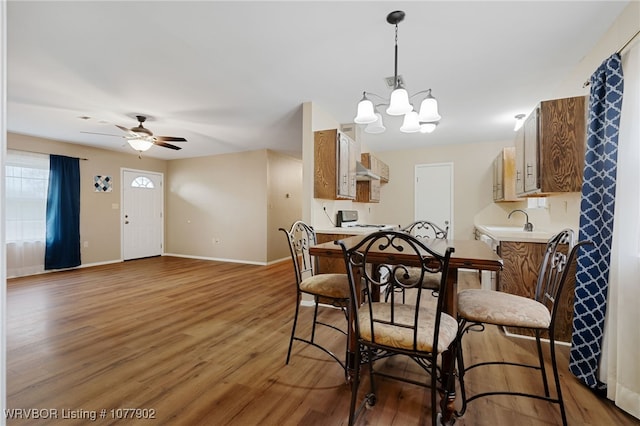 dining space featuring ceiling fan with notable chandelier, hardwood / wood-style flooring, and sink