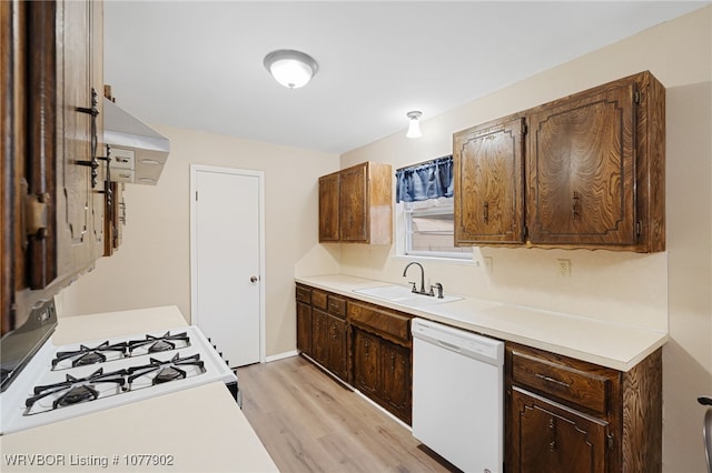 kitchen with sink, exhaust hood, white appliances, and light hardwood / wood-style floors