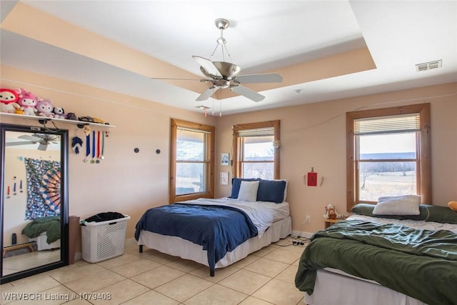 bedroom featuring light tile patterned floors, visible vents, baseboards, access to exterior, and a tray ceiling