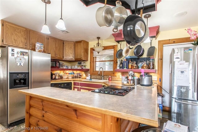 kitchen with stainless steel refrigerator with ice dispenser, black electric stovetop, freestanding refrigerator, a sink, and a peninsula