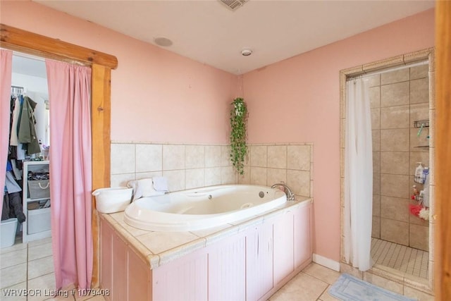 bathroom with a jetted tub, a tile shower, and tile patterned floors