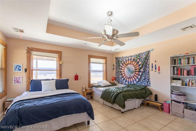 bedroom featuring multiple windows, visible vents, and a tray ceiling