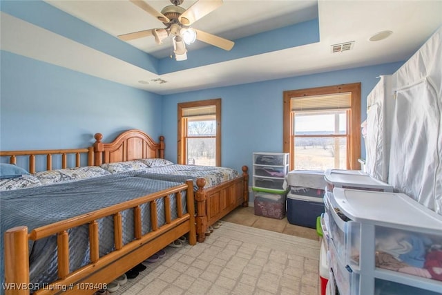 bedroom featuring a raised ceiling, visible vents, and a ceiling fan