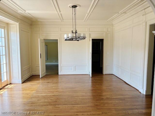 unfurnished dining area with wood-type flooring, a wealth of natural light, and a notable chandelier