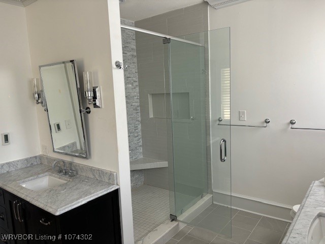 bathroom with tile patterned flooring, vanity, and walk in shower