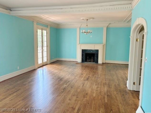 unfurnished living room with hardwood / wood-style floors, ornamental molding, a high end fireplace, and a chandelier