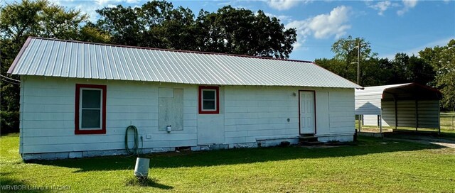 rear view of house featuring a carport and a yard