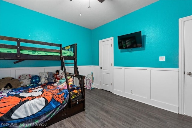 bedroom featuring dark wood-style flooring, wainscoting, and ceiling fan