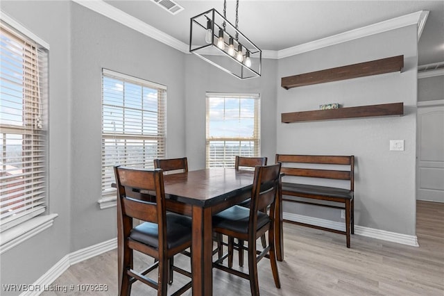 dining space with baseboards, visible vents, wood finished floors, crown molding, and a notable chandelier