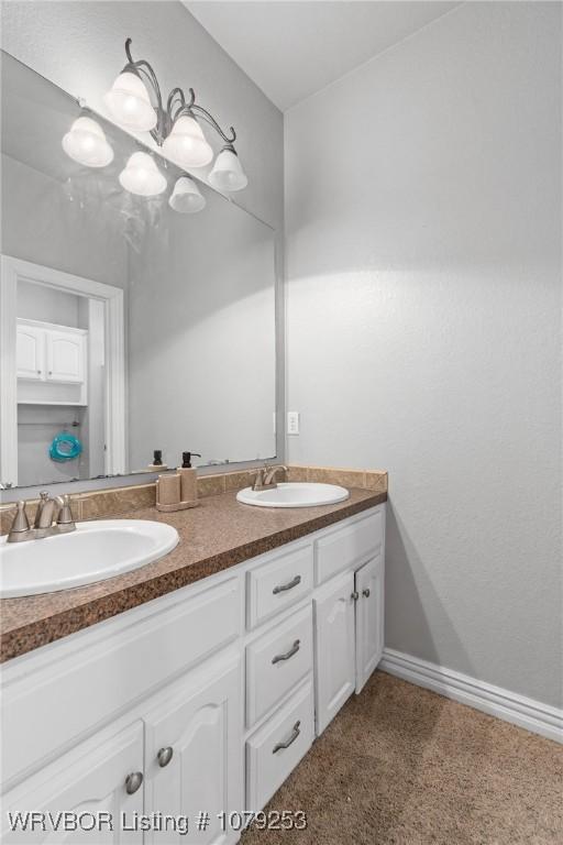 full bath with double vanity, baseboards, and a sink