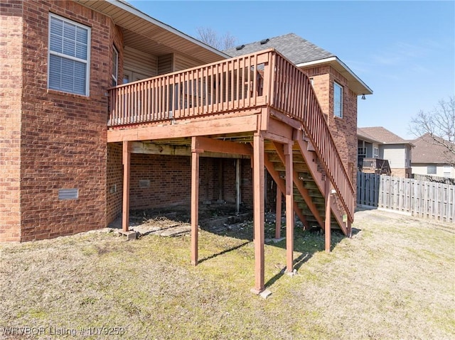 back of house featuring stairway, fence, a deck, a yard, and brick siding