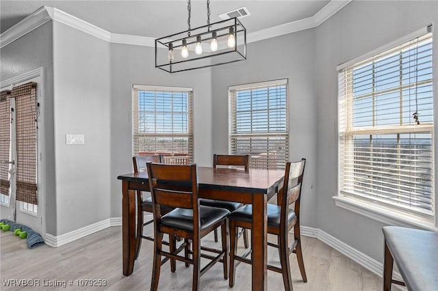 dining room featuring light wood-style floors, visible vents, and ornamental molding