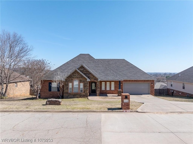 view of front of home featuring a garage, a shingled roof, concrete driveway, fence, and brick siding