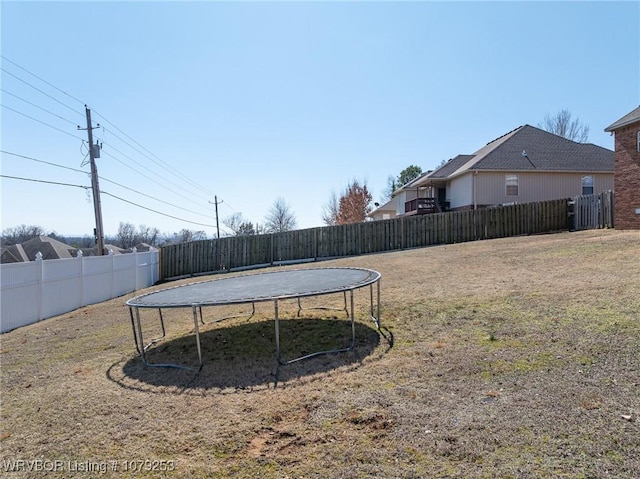 view of yard featuring a trampoline and a fenced backyard