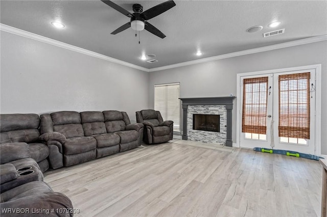 living room with visible vents, ceiling fan, wood finished floors, crown molding, and a fireplace