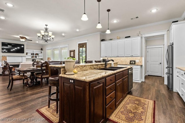 kitchen with dark wood-type flooring, white cabinets, a center island with sink, a kitchen bar, and stainless steel appliances