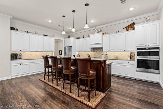 kitchen with white cabinets, appliances with stainless steel finishes, and an island with sink