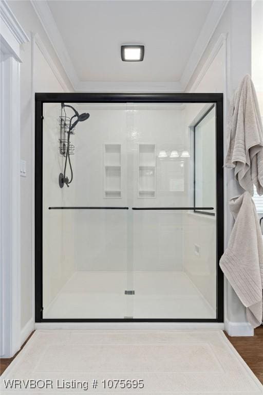 bathroom featuring hardwood / wood-style flooring, a shower with door, and ornamental molding