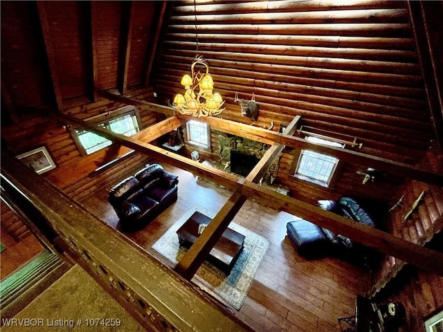 unfurnished living room with log walls, wood-type flooring, and a notable chandelier