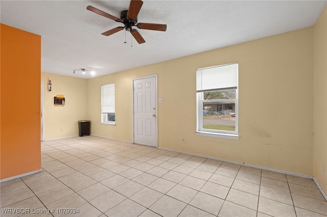spare room featuring baseboards, light tile patterned floors, and a ceiling fan
