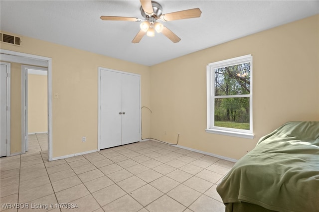 bedroom with baseboards, ceiling fan, visible vents, and light tile patterned floors