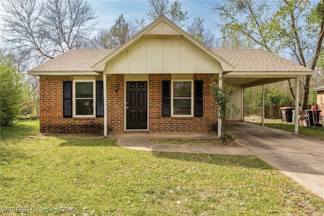 view of front of home with concrete driveway, a front yard, brick siding, an attached carport, and a shingled roof