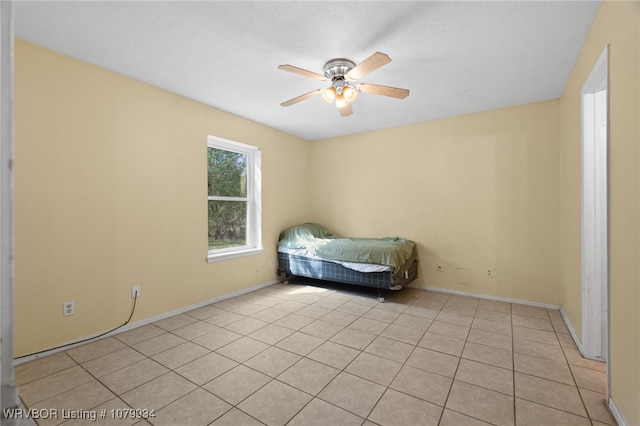 unfurnished bedroom featuring baseboards, light tile patterned floors, and a ceiling fan