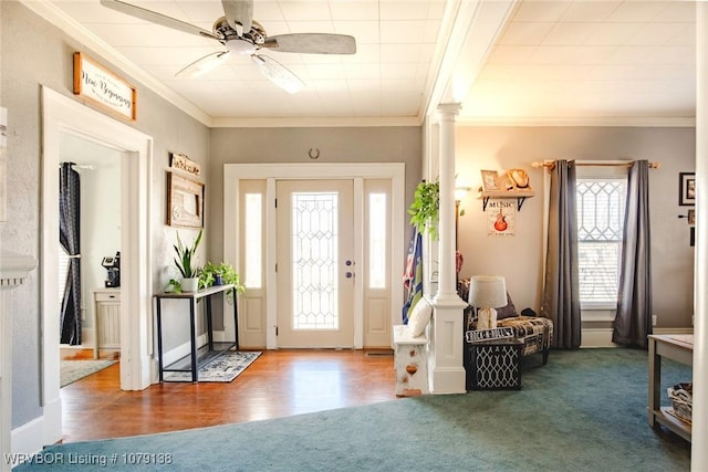 foyer with ornamental molding, dark carpet, and decorative columns