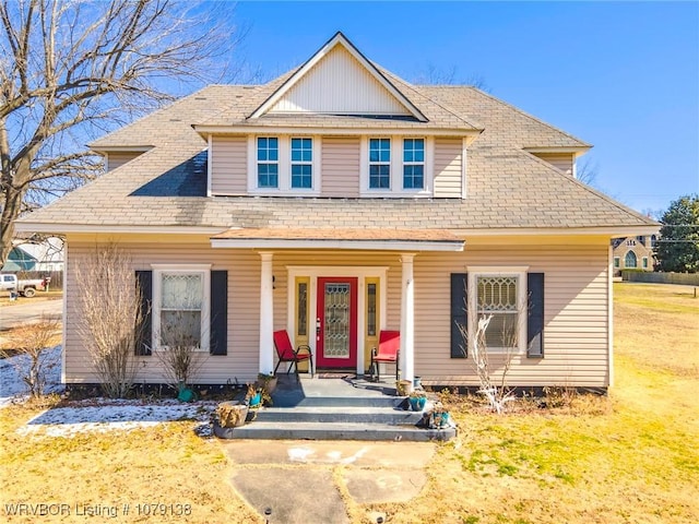 view of front of property featuring covered porch, roof with shingles, and a front yard