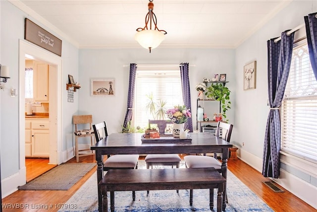 dining room featuring a wealth of natural light, light wood-style flooring, visible vents, and baseboards