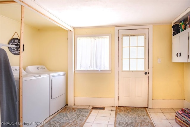 laundry area with a wealth of natural light, cabinet space, washer and clothes dryer, and light tile patterned floors