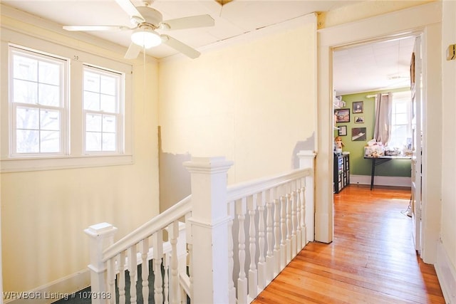 hall with light wood-type flooring, baseboards, and an upstairs landing