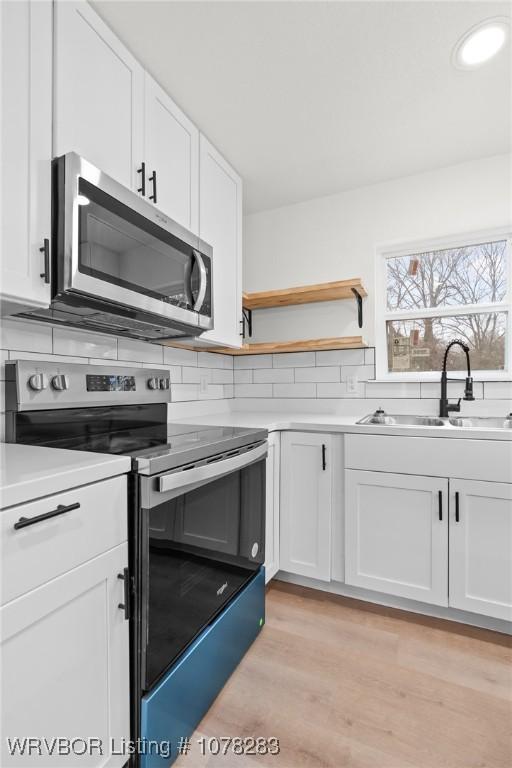 48 W Gary St, Greenwood, AR 72936 - kitchen with backsplash, sink, light hardwood / wood-style flooring, appliances with stainless steel finishes, and white cabinetry
