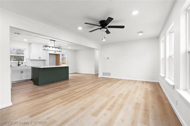 48 W Gary St, Greenwood, AR 72936 - unfurnished living room featuring ceiling fan, a healthy amount of sunlight, light hardwood / wood-style floors, and sink