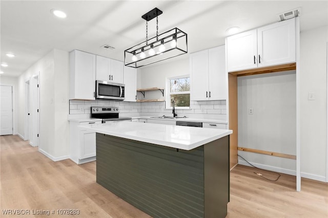 48 W Gary St, Greenwood, AR 72936 - kitchen with white cabinets, decorative light fixtures, sink, and appliances with stainless steel finishes