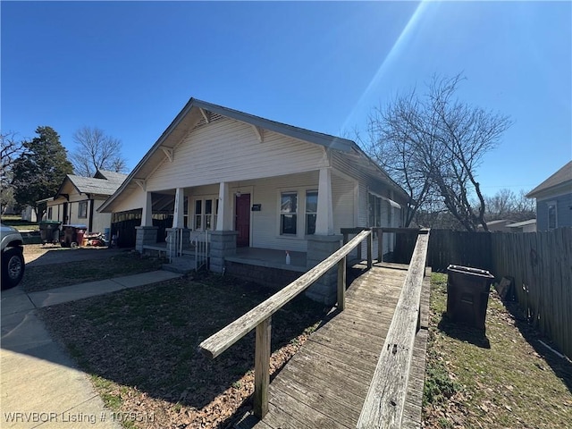 bungalow-style house with a porch, fence, and a garage