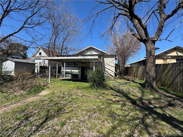 rear view of house with fence and a lawn