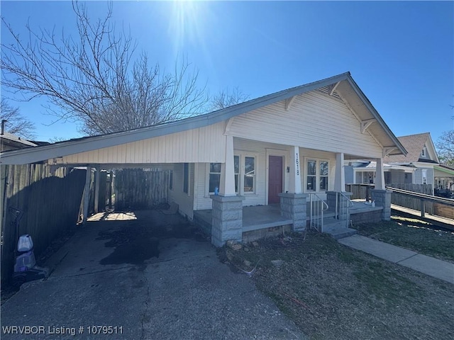 view of front facade featuring a carport, fence, covered porch, and driveway