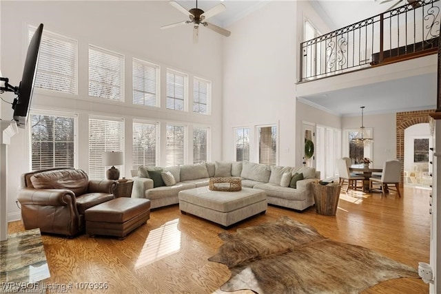 living area with a ceiling fan, plenty of natural light, crown molding, and wood finished floors