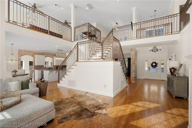 living room featuring stairs, wood finished floors, visible vents, and an inviting chandelier