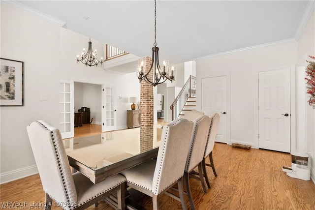 dining area with ornamental molding, french doors, light wood finished floors, and a chandelier