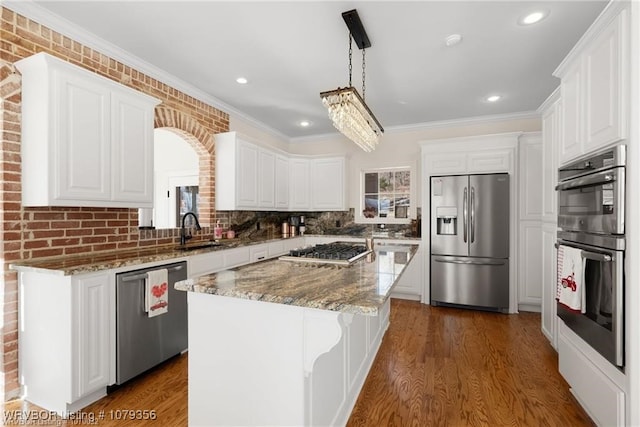 kitchen with stainless steel appliances, dark wood-style flooring, a sink, white cabinets, and a center island