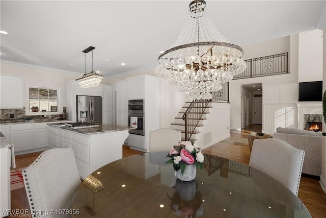 dining space featuring recessed lighting, a fireplace, wood finished floors, stairs, and crown molding